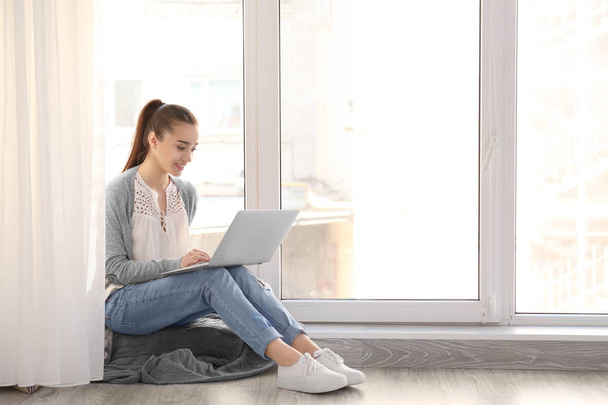 woman sitting on windowsill and using laptop - Fotoğraf, Görsel