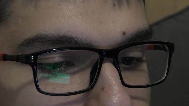 Mladý muž v brýlích vypadá zblízka na monitor - Záběry, video