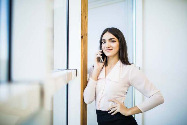 Business talk. Confident young businesswoman in suit talking on the mobile phone and smiling - Photo, image