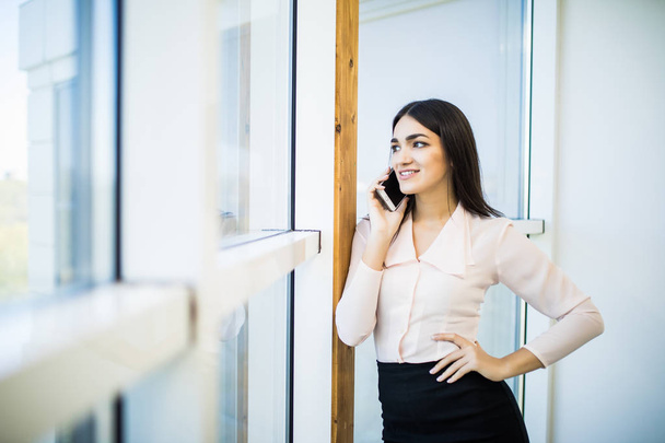 Business woman speak on phone near big office windows in modern office. - Foto, imagen