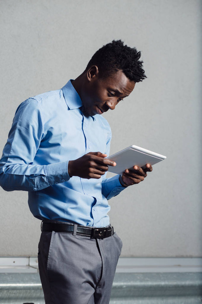 African american man in blue shirt using tablet PC - Foto, imagen