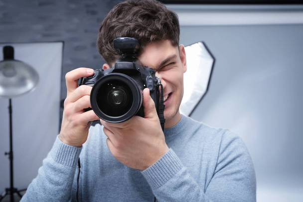 Young professional photographer with camera in studio - Foto, Bild