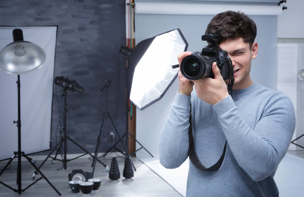 Young professional photographer with camera in studio - Фото, зображення