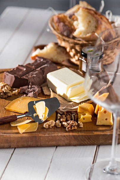 The different kind of cheese and walnuts on wooden background - Foto, afbeelding