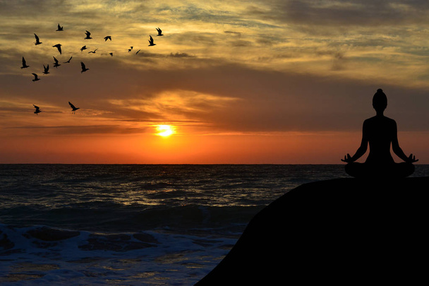 Žena přemýšlí v póze jógu na pláži při západu slunce - Fotografie, Obrázek