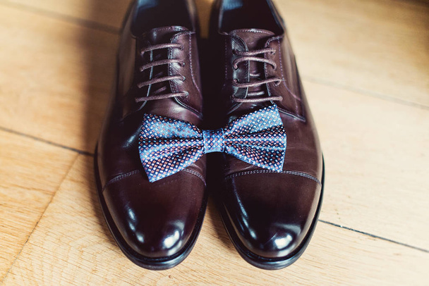 blue bow tie on a leather brown shoes. Grooms wedding morning. Close up of modern man accessories - Foto, imagen