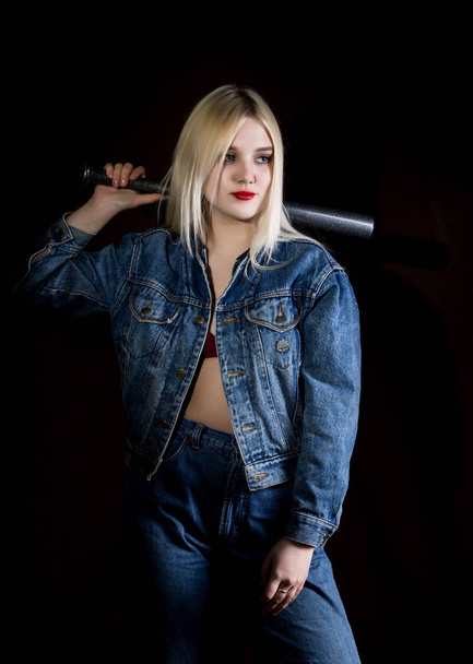 Criminal young woman with baseball bat, young hooligan in jeans and a denim jacket - Foto, afbeelding