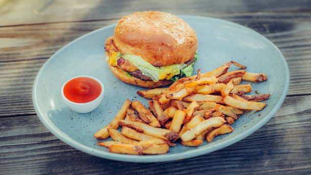 Fresh tasty burger and french fries on wooden table - Photo, image