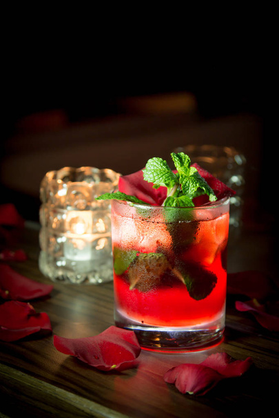 red cocktail with ice and mint on a black background - Foto, afbeelding