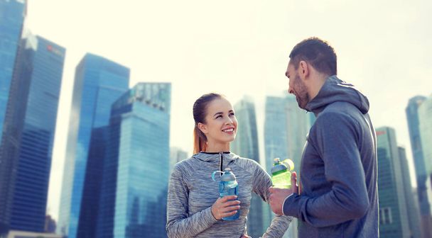 casal sorrindo com garrafas de água ao ar livre
 - Foto, Imagem