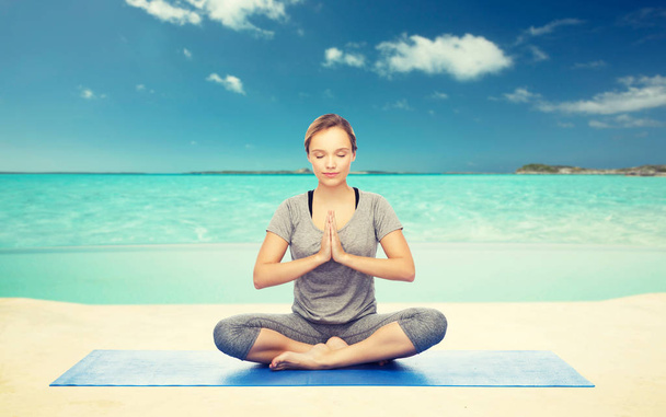 woman meditating in lotus yoga pose on beach - Valokuva, kuva