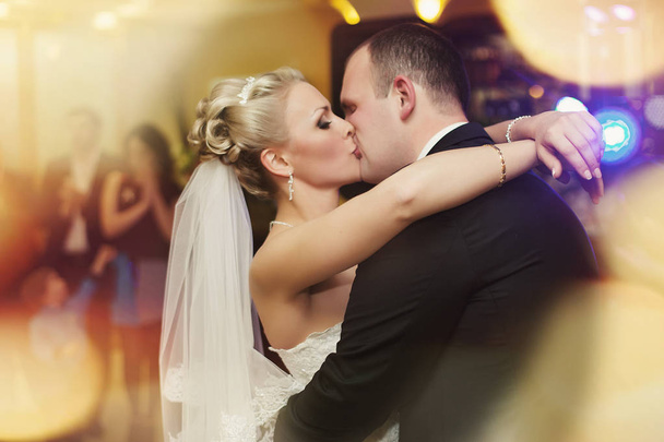 Blonde bride hodls her gracious hands on groom's shoulder while  - Zdjęcie, obraz