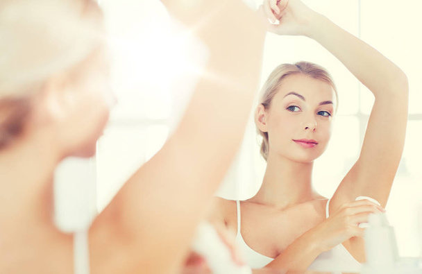 woman with antiperspirant deodorant at bathroom - Foto, afbeelding