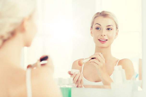 woman with makeup brush and powder at bathroom - Foto, Bild