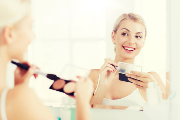 woman with makeup brush and foundation at bathroom - Foto, afbeelding