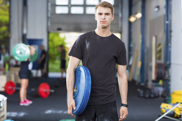 Determined Athlete Carrying Weight Plate In Health Club - Photo, Image