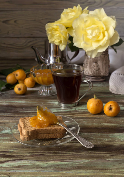 Větve s plody mišpule, marmeláda a čaj na dřevěný stůl  - Fotografie, Obrázek
