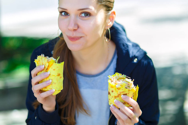 Dziewczyna zjada shawarma na ulicy. - Zdjęcie, obraz