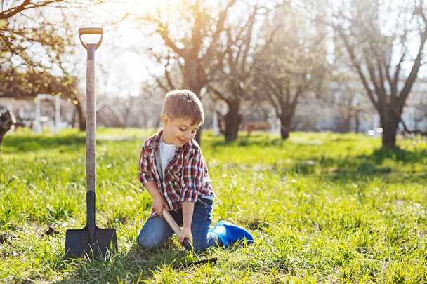 Smiling boy scooping ground in yard - Zdjęcie, obraz