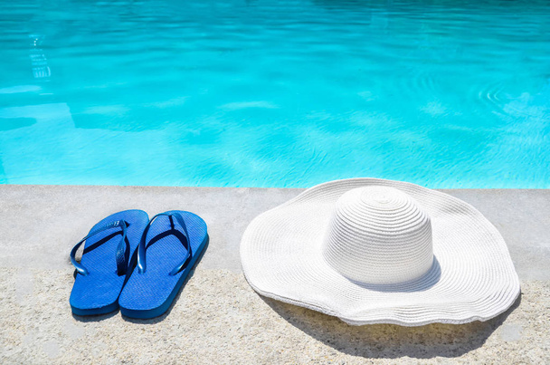 Summer hat and flip flops near the pool - Fotoğraf, Görsel