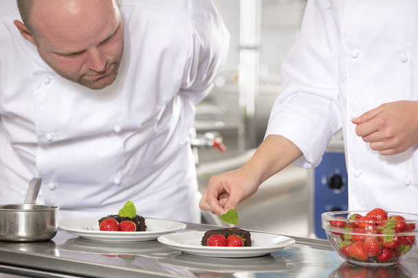Professionele chefs versieren dessert cake met citroen-blad - Foto, afbeelding