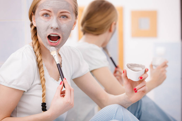 Mutlu genç kadın yüz çamur maskesi uygulama - Fotoğraf, Görsel
