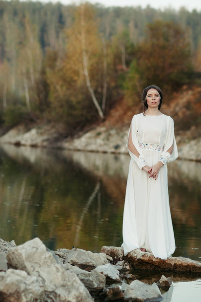 A girl in a white dress on the shore of a pond - Фото, зображення