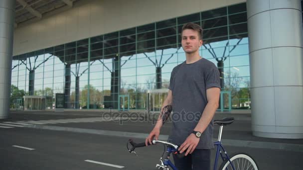 Man standing and holding his bicycle near the airport slow motion - Video