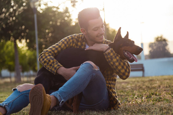 Handsome young man playing with his dog in the park. - Foto, imagen