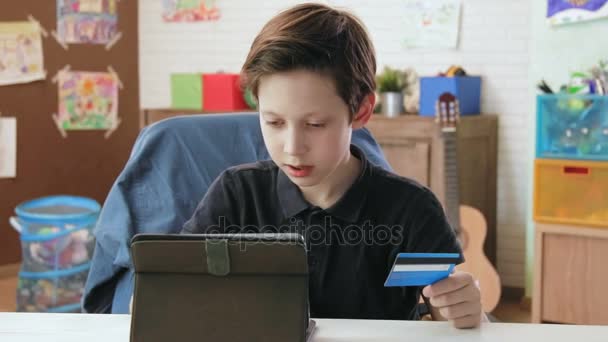 Симпатичный маленький мальчик делает покупки в Интернете, вводя номер кредитной карты с помощью цифрового планшета, и счастлив после совершения покупки
 - Кадры, видео