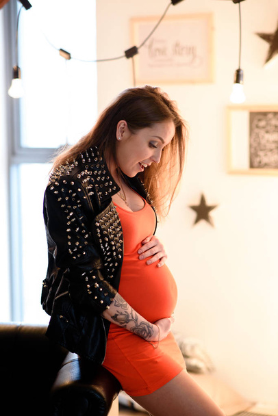 Pregnant girl with tattoo in a red dress. - Photo, Image