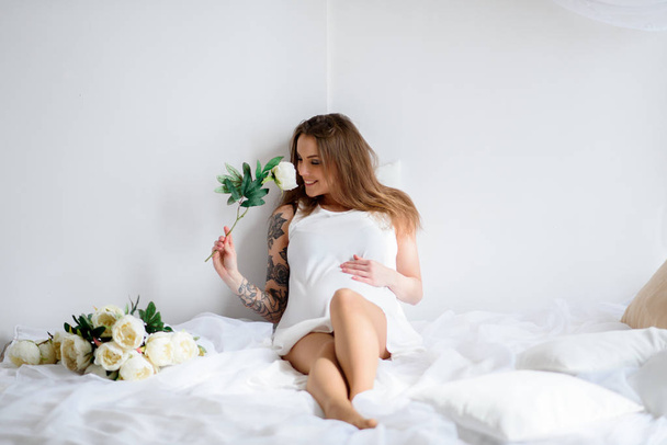Pregnant girl with tattoo in a white dress. - Φωτογραφία, εικόνα