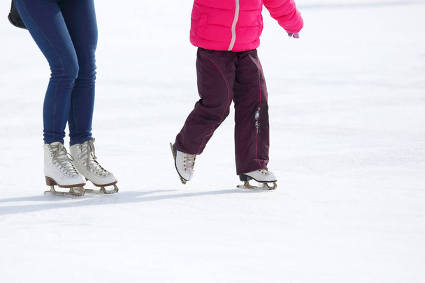 the legs of an adult and child skating on the ice rink - Фото, изображение