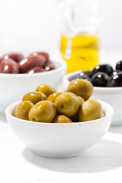 assortment of different kinds of organic olives on white table - Foto, afbeelding