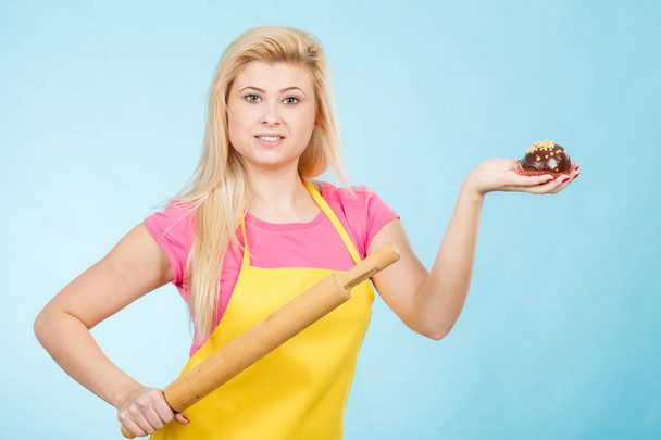 Woman holding cupcake and rolling pin wearing apron - Φωτογραφία, εικόνα
