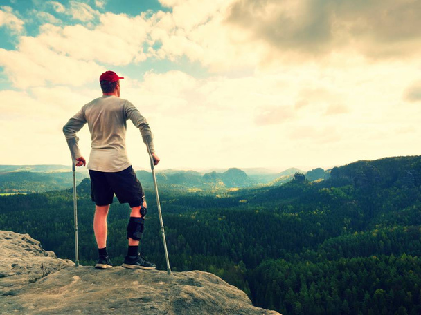 Happy man with broken leg in immobilizer and medicine pole stay finnaly on  peak. - Photo, Image