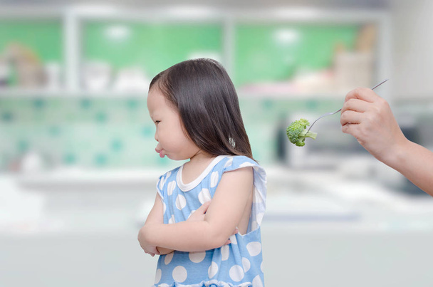 meisje weigeren te eten broccoli van haar moeder - Foto, afbeelding