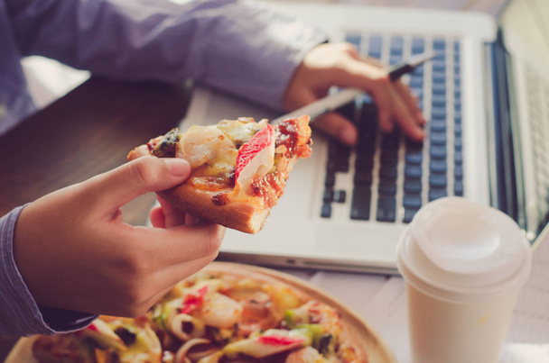 L'équipe d'affaires mange de la pizza au travail tout en travaillant
 - Photo, image