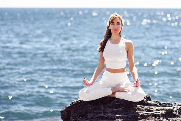 Młoda kobieta robi joga na plaży, ubraniach, biały - Zdjęcie, obraz