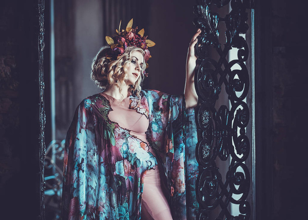 Beautiful woman in a dress of floral colors stands in the palace - Фото, зображення