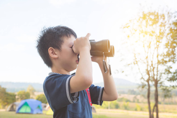 boy looking by binoculars at camping site - Zdjęcie, obraz
