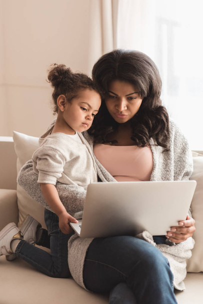 Madre e hija usando laptop
  - Foto, imagen