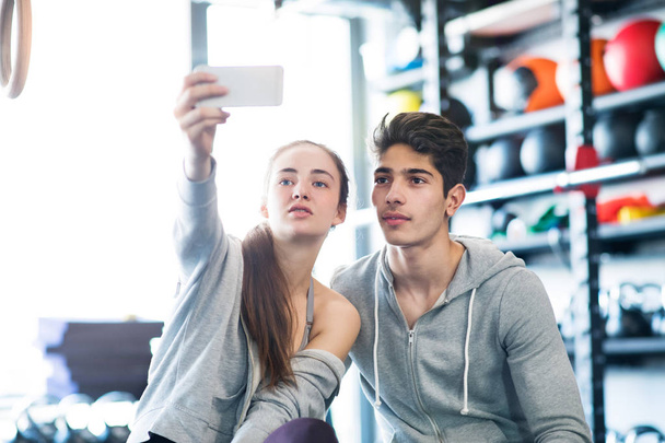 Couple dans la salle de gym Crossfit moderne avec smartphone
. - Photo, image