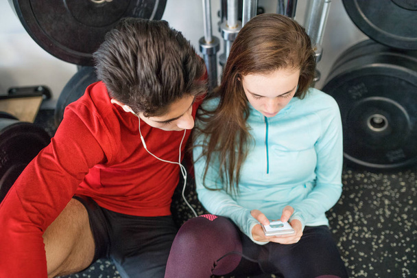 Fit couple in modern crossfit gym with smartphone. - Foto, afbeelding