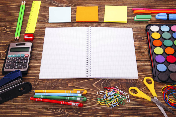 Opened blank notebook, frame of school supplies over a  retro wooden background. With copy space Back to school concept. - Photo, Image