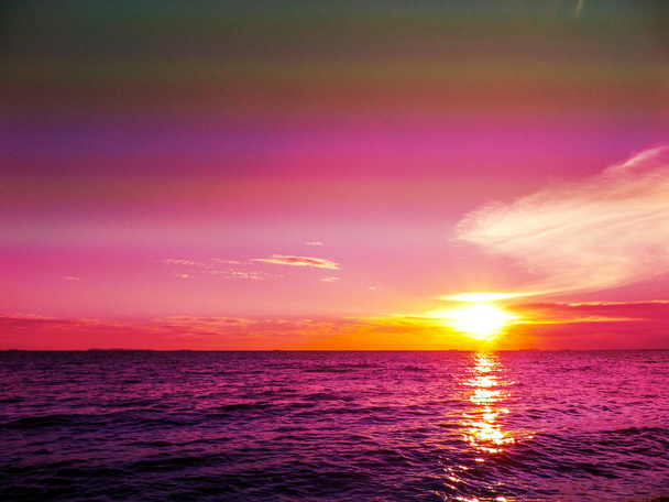 Auringonlasku ja pilvi horisontissa ja tumma violetti vesi
 - Valokuva, kuva
