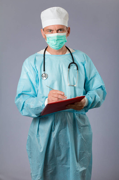 Arzt mit Stethoskop und Gesichtsmaske mit Stift und  - Foto, Bild