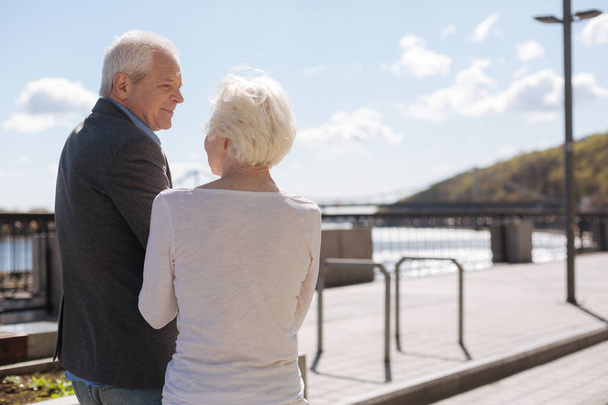 Glad pensioner enjoying promenade with his lovely wife - Foto, imagen