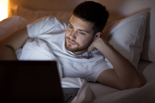 young man with laptop in bed at home bedroom - Foto, immagini