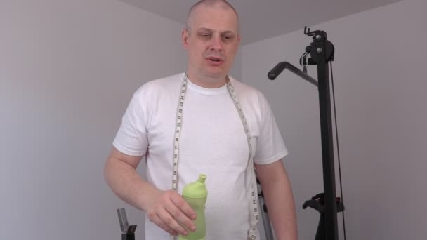 Unavený muž s láhev s vodou a opatření pásky po cvičení - Záběry, video